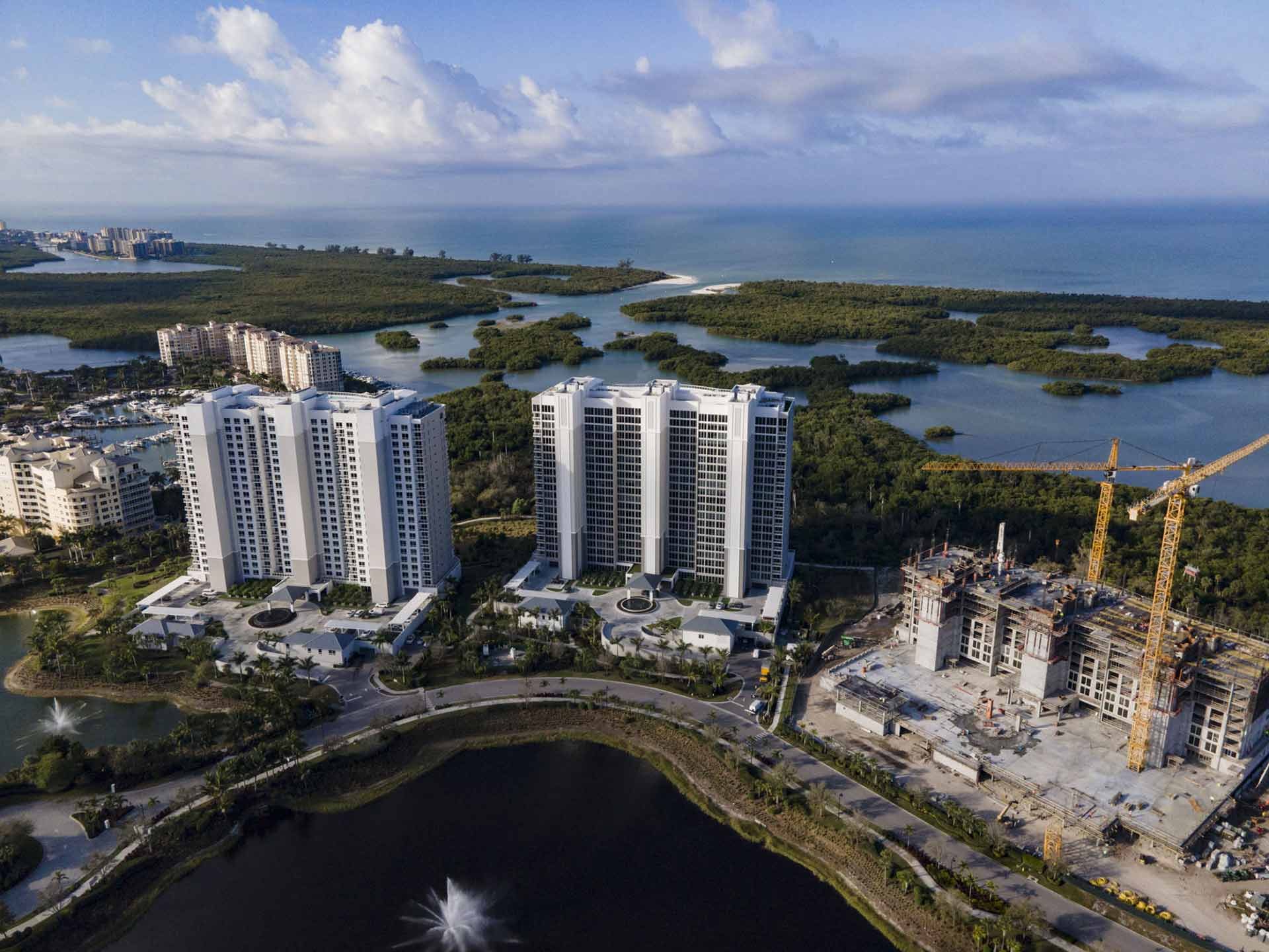Drone aerial of the Kalea Bay towers along the Naples Gulf coastline and mangroves